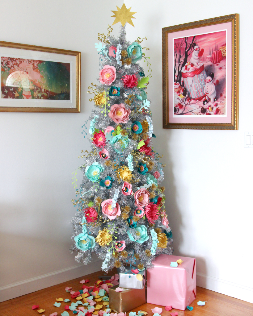a silver Treetopia Christmas tree decorated in handmade pastel paper flowers with gold accents